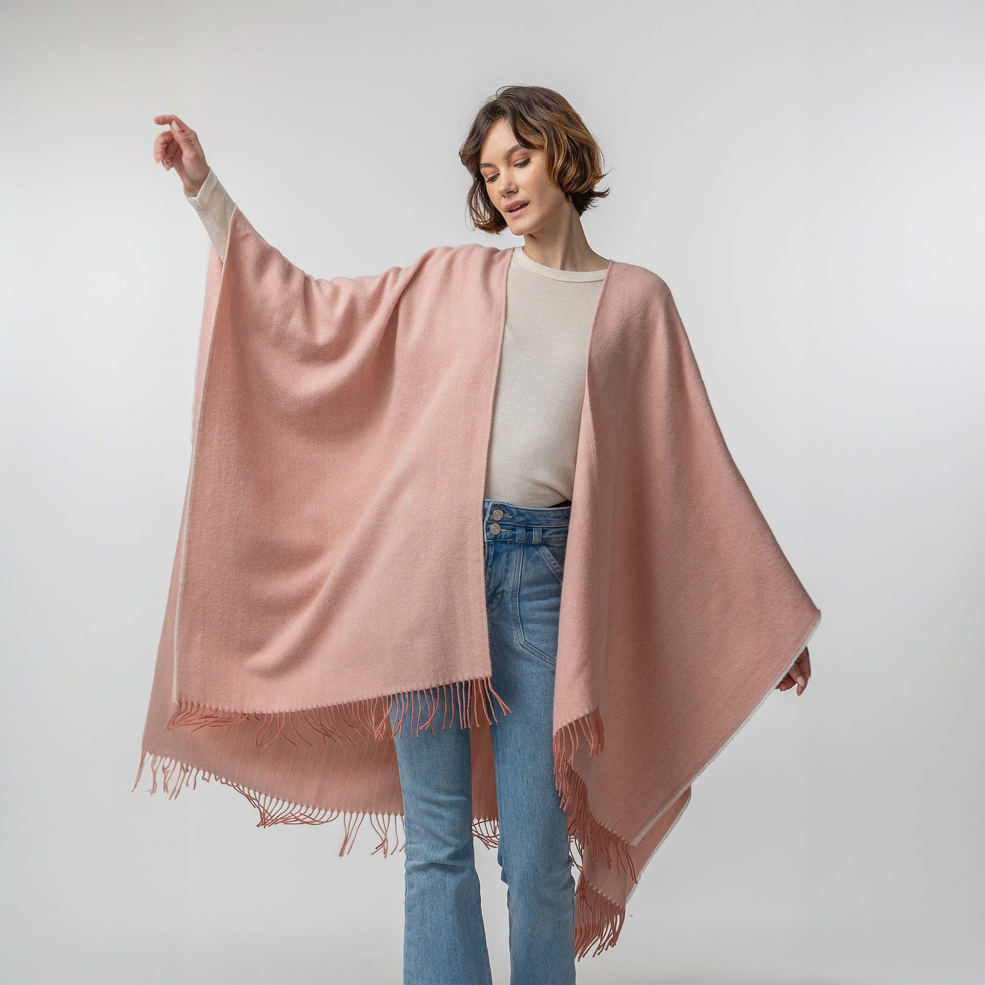 the Alicia Adams Alpaca Classic Cape, a timeless piece available in solid or herringbone patterns. With over 100 colors to choose from, it's perfect for any style preference. The cape effortlessly layers over sweaters and jackets, making it a must-have staple in every wardrobe. This color is Melon
