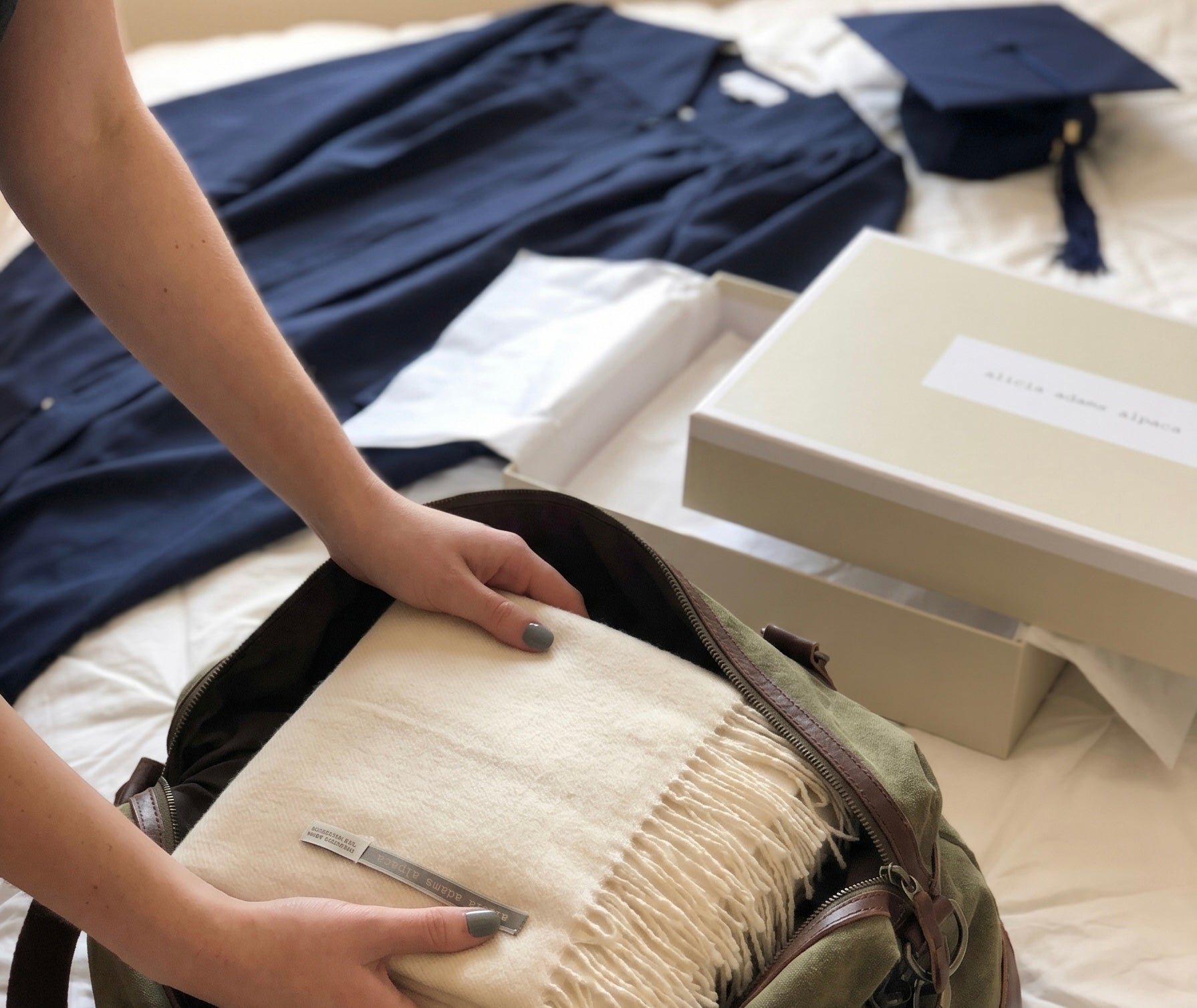 Person packing graduation attire and accessories into a backpack.