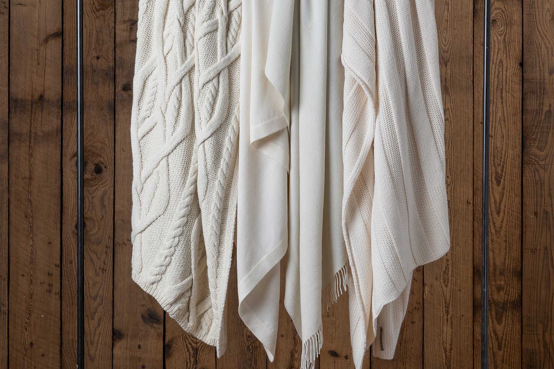 A collection of cream-colored fabric drapes hanging against a wooden background.