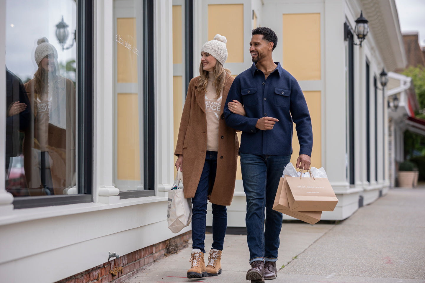A couple walking together, holding hands and carrying a takeout bag.