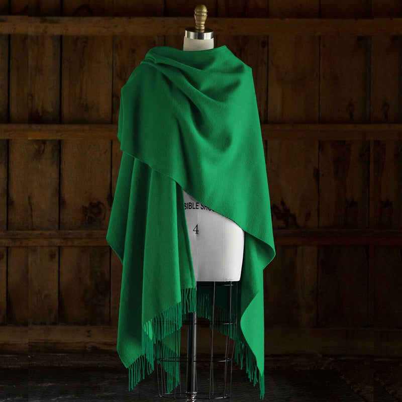 the Alicia Adams Alpaca Classic Cape, a timeless piece available in solid or herringbone patterns. With over 100 colors to choose from, it's perfect for any style preference. The cape effortlessly layers over sweaters and jackets, making it a must-have staple in every wardrobe.  This color is Green