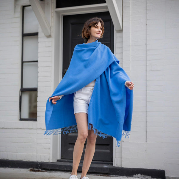 the Alicia Adams Alpaca Classic Cape, a timeless piece available in solid or herringbone patterns. With over 100 colors to choose from, it's perfect for any style preference. The cape effortlessly layers over sweaters and jackets, making it a must-have staple in every wardrobe.  This color is Sky Blue
