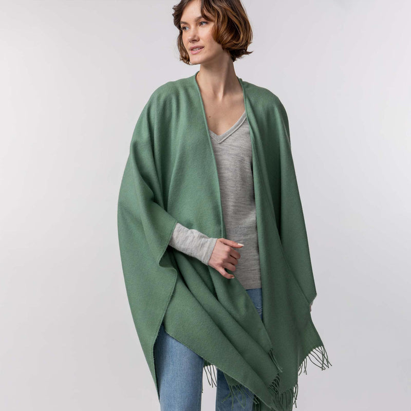 the Alicia Adams Alpaca Classic Cape, a timeless piece available in solid or herringbone patterns. With over 100 colors to choose from, it's perfect for any style preference. The cape effortlessly layers over sweaters and jackets, making it a must-have staple in every wardrobe.  This color is Evergreen - swatch-2