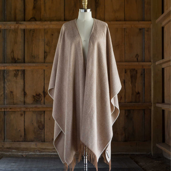 the Alicia Adams Alpaca Classic Cape, a timeless piece available in solid or herringbone patterns. With over 100 colors to choose from, it's perfect for any style preference. The cape effortlessly layers over sweaters and jackets, making it a must-have staple in every wardrobe.  This color is Cognac