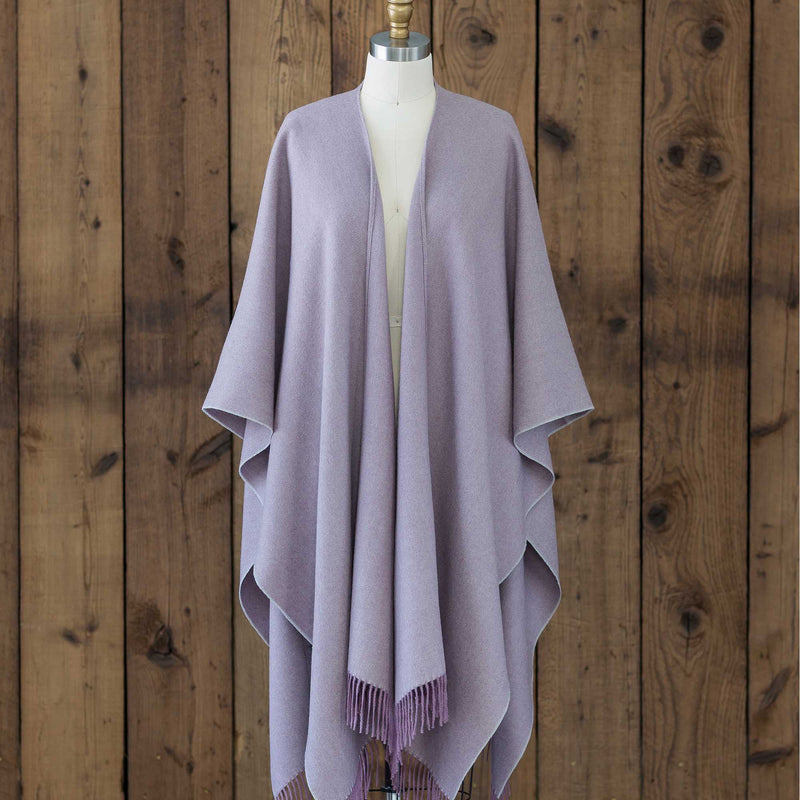 the Alicia Adams Alpaca Classic Cape, a timeless piece available in solid or herringbone patterns. With over 100 colors to choose from, it's perfect for any style preference. The cape effortlessly layers over sweaters and jackets, making it a must-have staple in every wardrobe.  This color is Pale Orchid