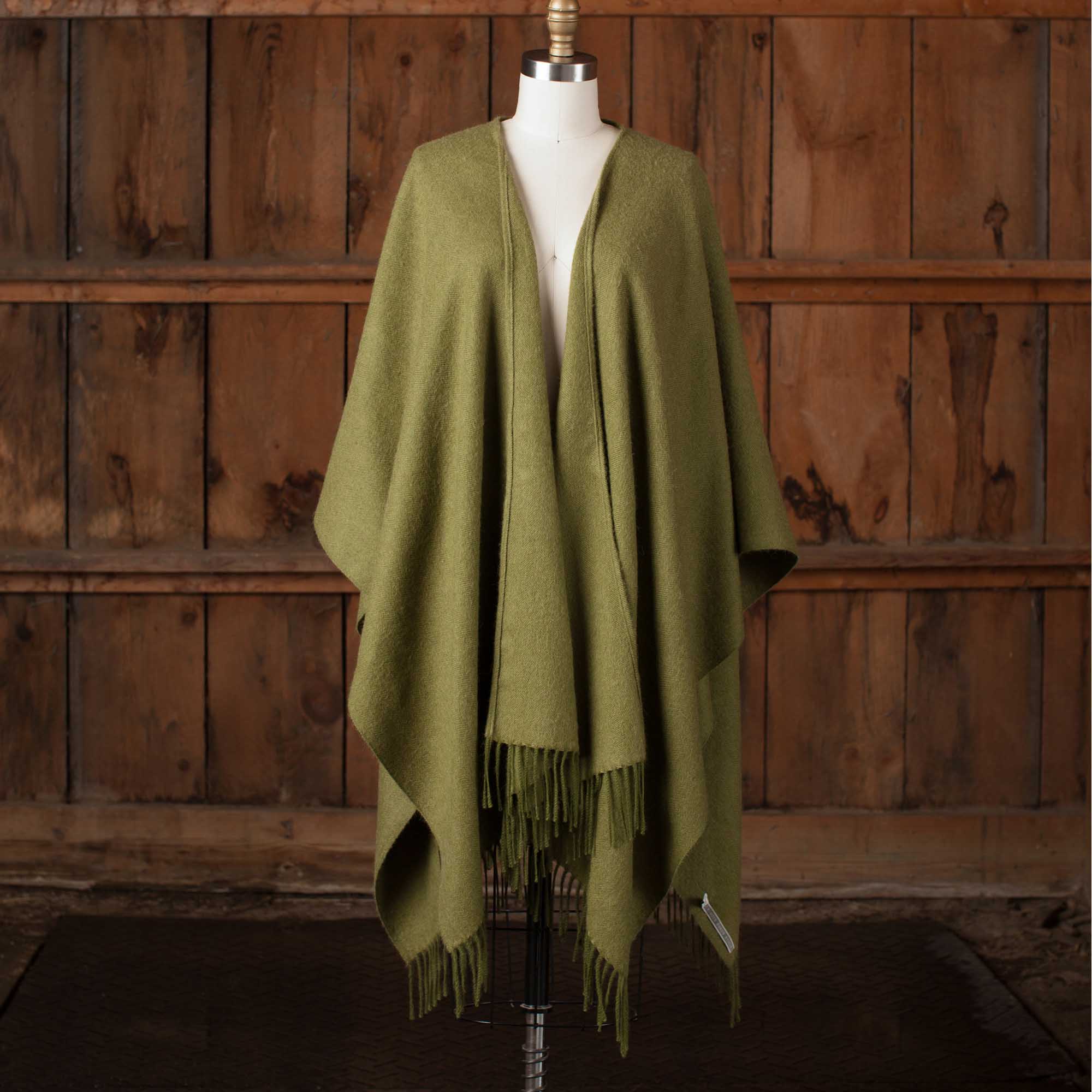 the Alicia Adams Alpaca Classic Cape, a timeless piece available in solid or herringbone patterns. With over 100 colors to choose from, it's perfect for any style preference. The cape effortlessly layers over sweaters and jackets, making it a must-have staple in every wardrobe.  This color is Hunter