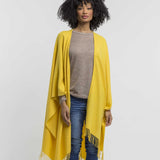 the Alicia Adams Alpaca Classic Cape, a timeless piece available in solid or herringbone patterns. With over 100 colors to choose from, it's perfect for any style preference. The cape effortlessly layers over sweaters and jackets, making it a must-have staple in every wardrobe.  This color is Lemon